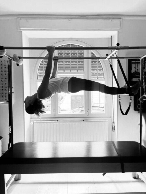 Exercice de Pilates Hanging réalisé sur l’appareil Cadillac, illustrant le travail de gainage, de contrôle et d’alignement du corps